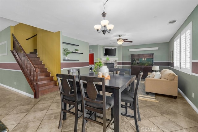 dining room featuring light tile patterned floors, ceiling fan with notable chandelier, visible vents, and stairs