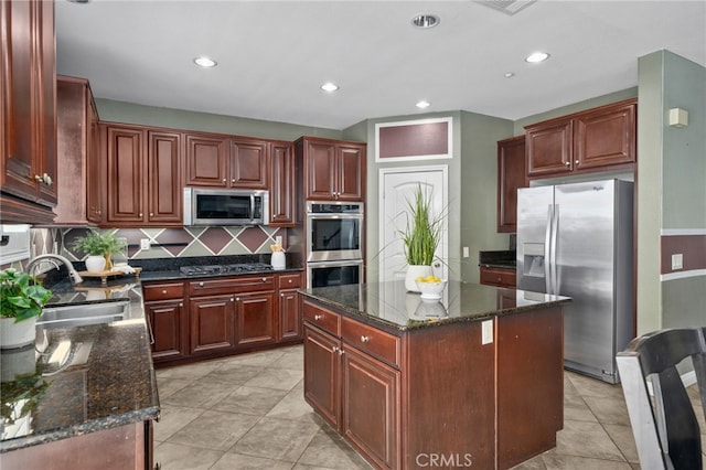 kitchen with tasteful backsplash, a kitchen island, appliances with stainless steel finishes, dark stone countertops, and a sink