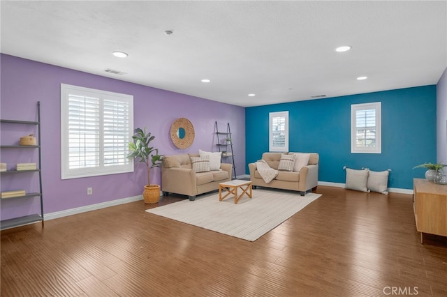 living room with baseboards, visible vents, wood finished floors, and recessed lighting