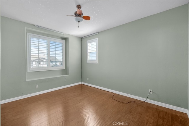 unfurnished room with ceiling fan, baseboards, and wood finished floors