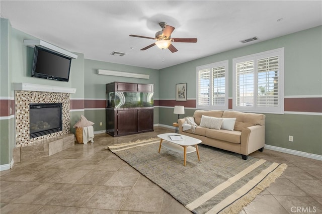 living room with baseboards, ceiling fan, visible vents, and a tiled fireplace