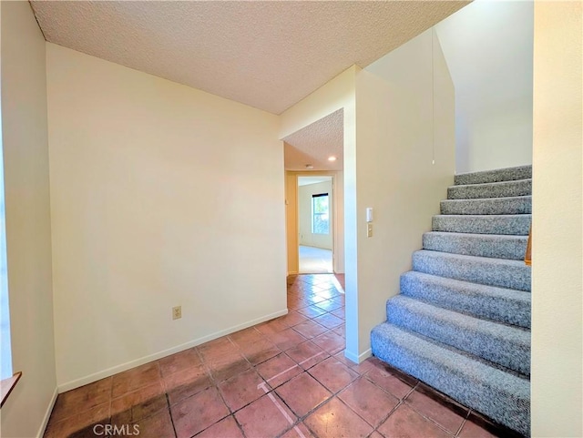 staircase with baseboards, a textured ceiling, and tile patterned floors