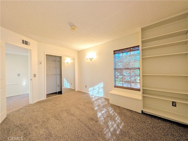 carpeted spare room with visible vents, a textured ceiling, and baseboards