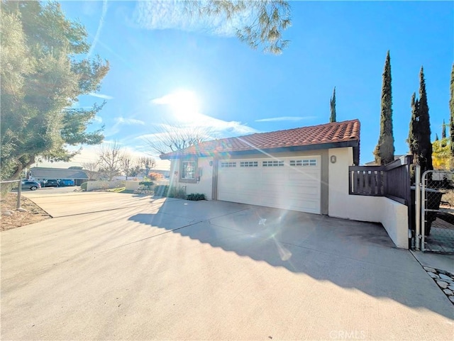 view of front of property with concrete driveway, a tile roof, a gate, and stucco siding