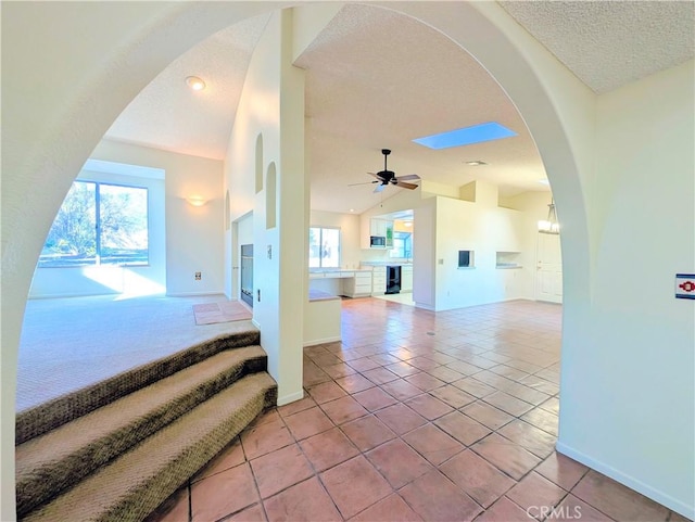 interior space with lofted ceiling, a textured ceiling, baseboards, and tile patterned floors