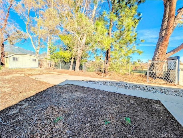 view of yard featuring a patio area, a fenced backyard, and an outbuilding