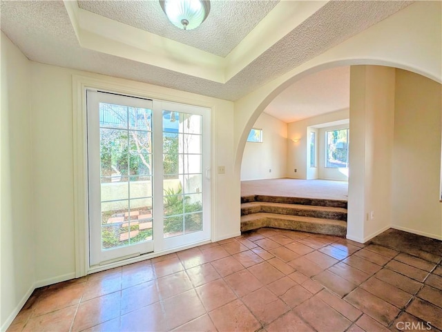 doorway to outside with a textured ceiling and tile patterned floors