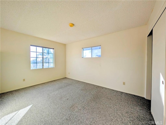 spare room with carpet floors, baseboards, and a textured ceiling