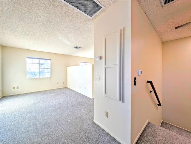 interior space with a textured ceiling, carpet floors, and visible vents