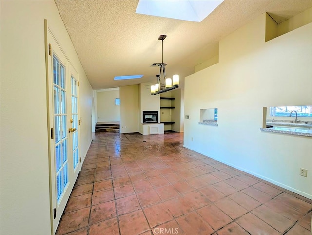 unfurnished living room with a notable chandelier, visible vents, a textured ceiling, baseboards, and tile patterned floors