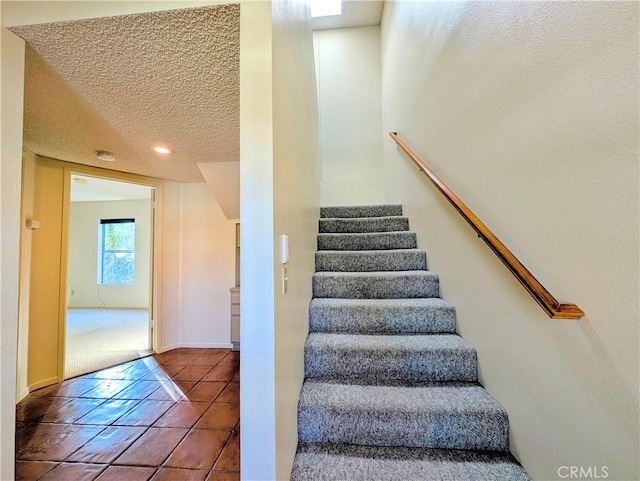 stairs with tile patterned flooring, a textured ceiling, baseboards, and recessed lighting