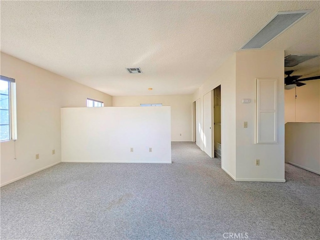 carpeted spare room featuring baseboards, visible vents, and a textured ceiling