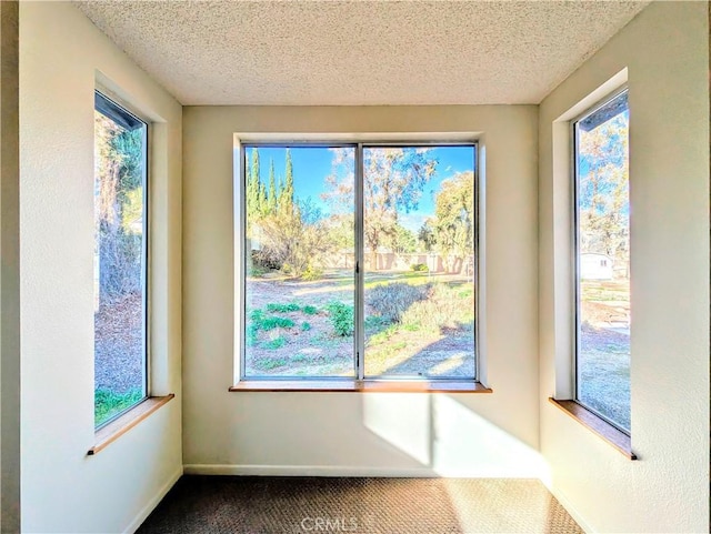 doorway to outside with dark colored carpet, a textured ceiling, and baseboards