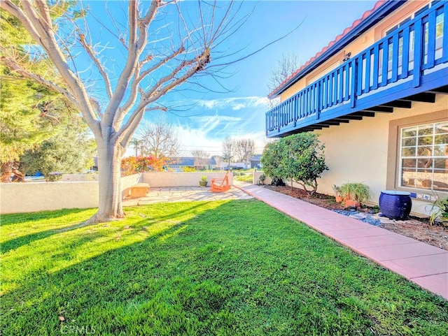 view of yard featuring fence and a balcony