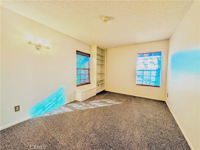 spare room featuring a textured ceiling, carpet floors, built in features, and baseboards