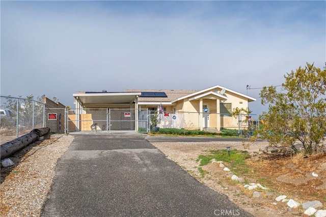 view of front of home featuring aphalt driveway, an attached carport, fence, and a gate