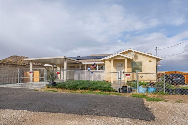 view of front facade featuring a fenced front yard, a carport, solar panels, and a gate