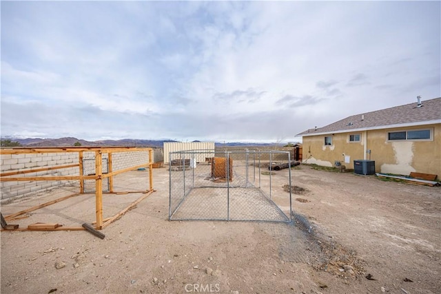 view of yard with fence, central AC unit, and a gate