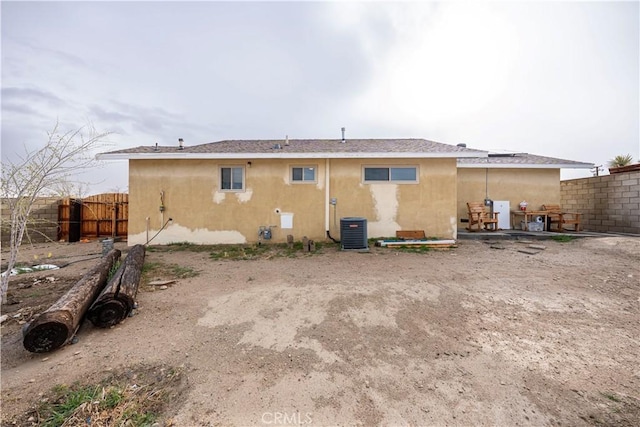 back of property featuring cooling unit, fence, and stucco siding