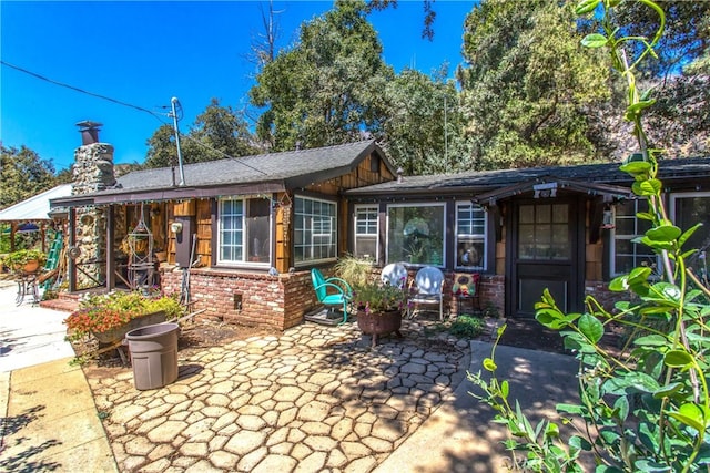 exterior space featuring brick siding, a patio, and a chimney