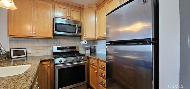 kitchen with light brown cabinetry, appliances with stainless steel finishes, stone counters, and backsplash