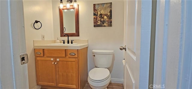 bathroom featuring toilet, baseboards, and vanity