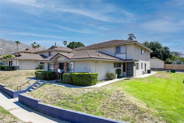 traditional-style home featuring stucco siding, fence, and a front yard