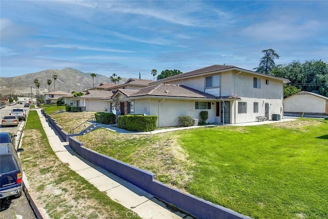 view of front of home featuring a front yard, a mountain view, and stucco siding