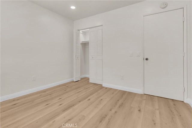 unfurnished bedroom featuring a closet, recessed lighting, light wood-style flooring, and baseboards