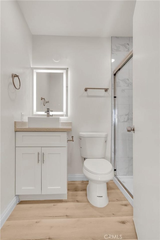 full bathroom with a stall shower, vanity, toilet, and wood finished floors