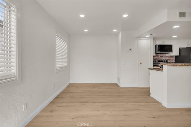 interior space featuring white cabinets, light wood finished floors, visible vents, and stainless steel appliances