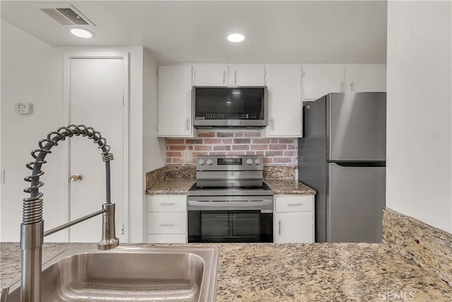 kitchen featuring visible vents, white cabinets, decorative backsplash, stainless steel appliances, and a sink