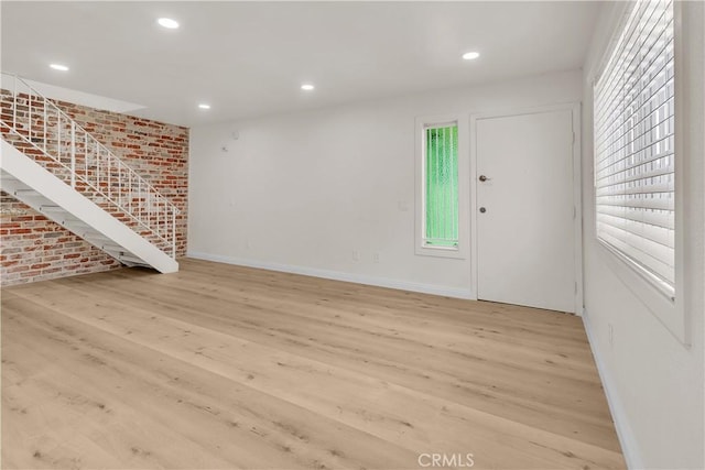 entryway with recessed lighting, brick wall, wood finished floors, baseboards, and stairway