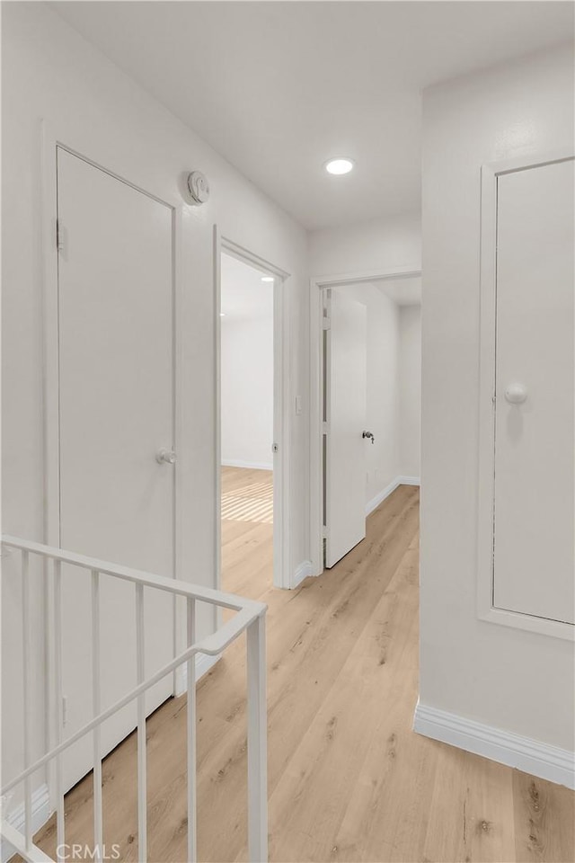 corridor with recessed lighting, light wood-type flooring, and baseboards