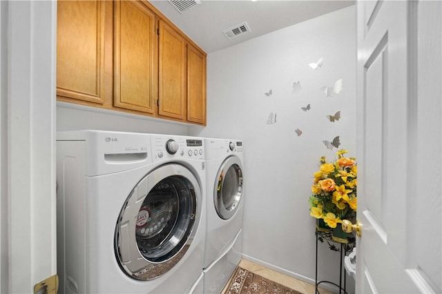 clothes washing area with visible vents, cabinet space, and washer and clothes dryer