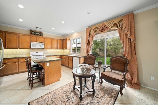 kitchen with white appliances, ornamental molding, decorative backsplash, and a center island