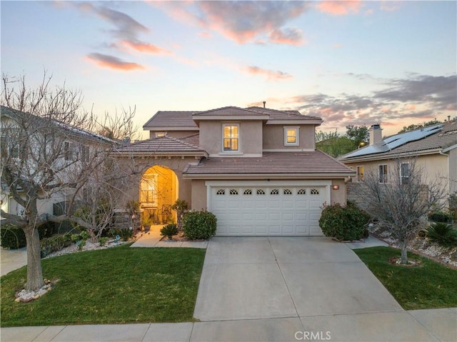 view of front facade featuring a garage, concrete driveway, a tile roof, a front lawn, and stucco siding