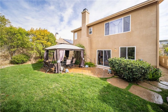 rear view of property with a gazebo, a yard, a patio, and stucco siding