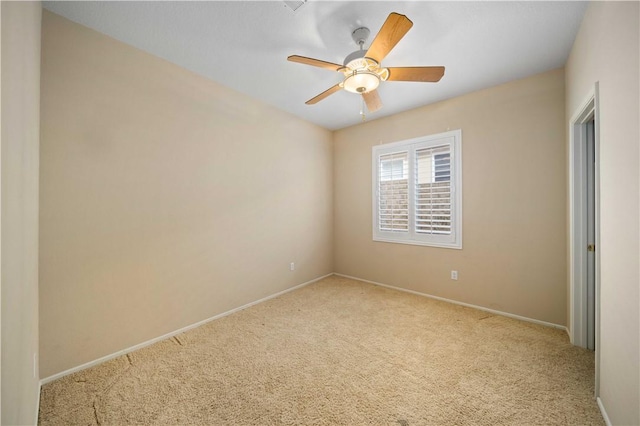 carpeted spare room featuring ceiling fan and baseboards