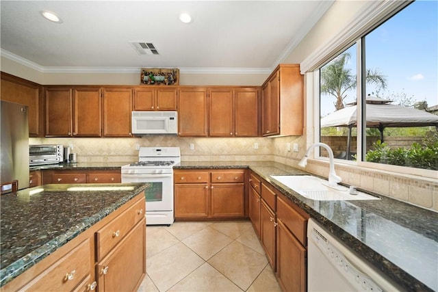 kitchen with white appliances, visible vents, ornamental molding, brown cabinets, and a sink