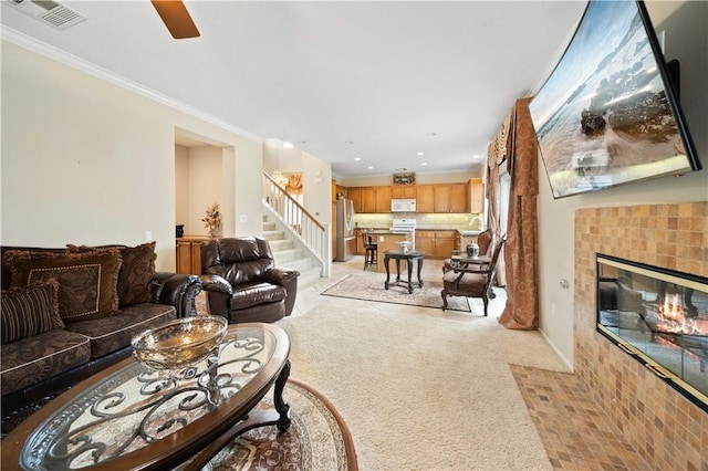 living room with light colored carpet, a fireplace, visible vents, stairs, and crown molding