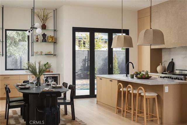 kitchen with modern cabinets, a kitchen bar, a center island with sink, and decorative backsplash