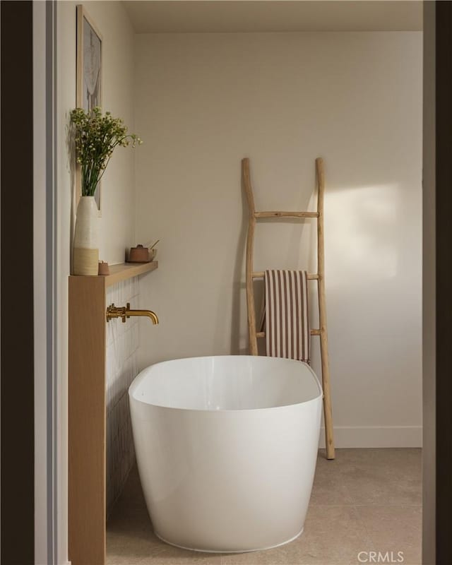 bathroom with baseboards, a freestanding bath, and tile patterned floors