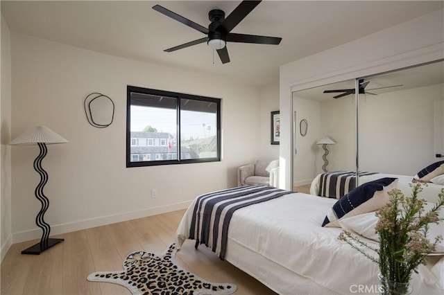 bedroom featuring a ceiling fan, a closet, baseboards, and wood finished floors