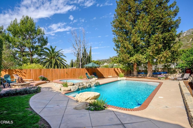 view of swimming pool featuring a patio, an outdoor fire pit, a fenced backyard, an in ground hot tub, and a fenced in pool