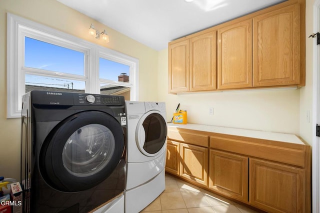 laundry room featuring light tile patterned floors, cabinet space, and independent washer and dryer