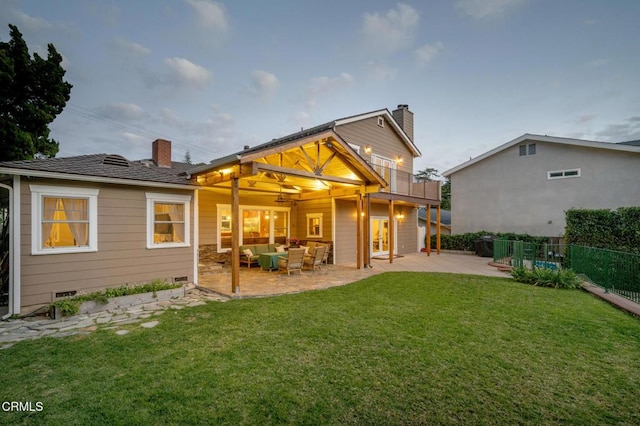 rear view of house featuring a chimney, fence, a lawn, and a patio