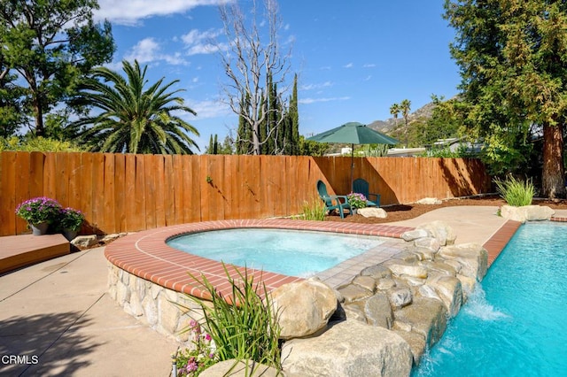 view of swimming pool featuring a patio area, fence, a pool, and an in ground hot tub