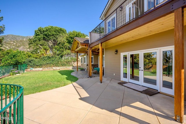 view of patio / terrace featuring french doors, fence, a balcony, and a mountain view