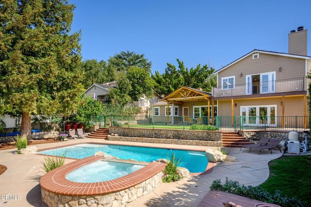 view of swimming pool featuring a patio area, fence, a fenced in pool, and an in ground hot tub